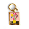 Keychain with colorful floral design on a pink background.