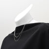 A dainty layering necklace in silver. It is made up of two intertwined sterling chains; one linked and one smooth. They're placed around a mannequin's neck.