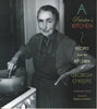 A book cover featuring a black and white photograph of a woman with a light skin tone wearing an apron, cooking. The text reads: "A Painter's Kitchen: Recipes from the Kitchen of Georgia O'Keeffe."
