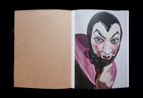 Look inside a book depicting a photograph of a person in a vampire mask.