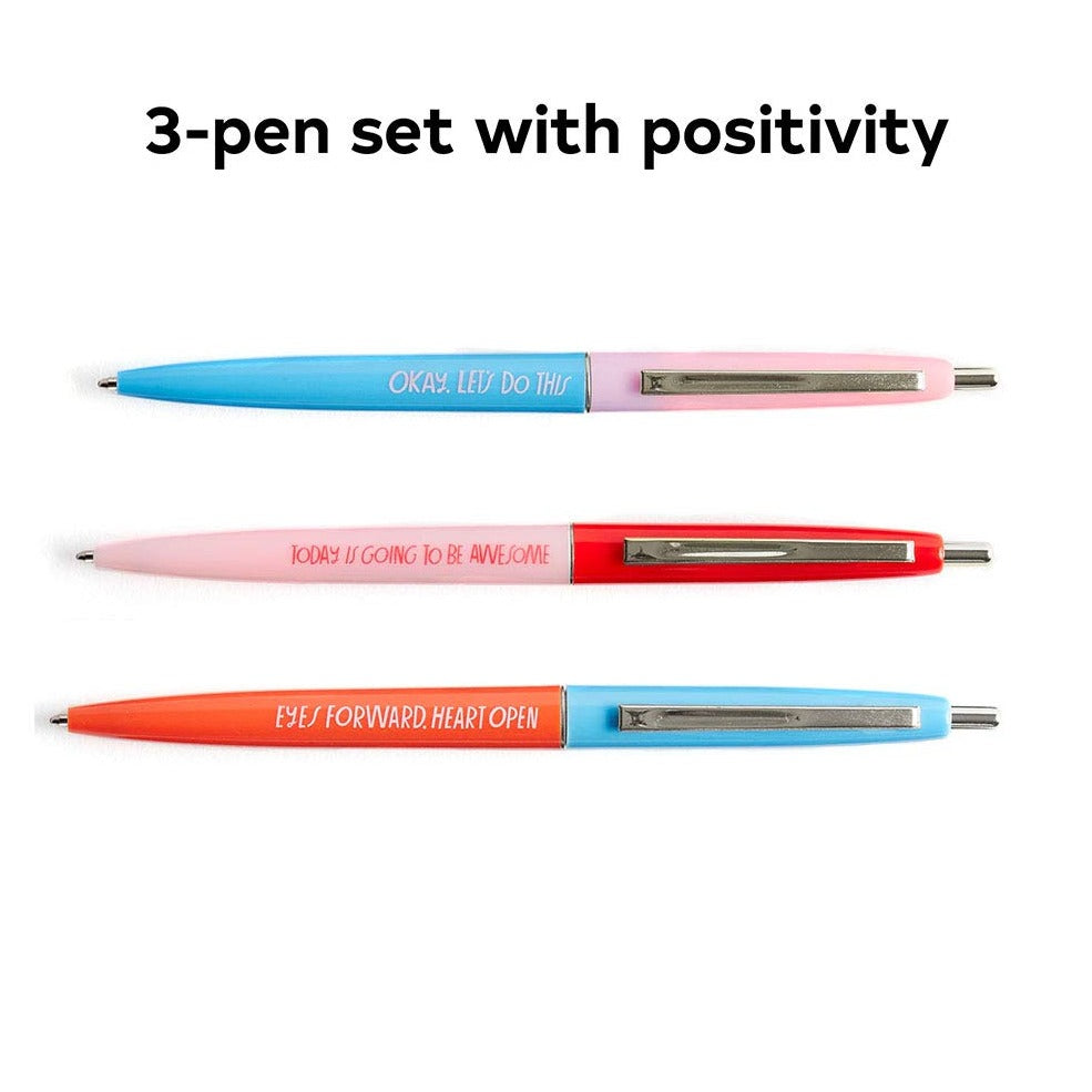 Three pens lying next to each other. They are pink and blue and have different text on them, such as "Okay let's do this".