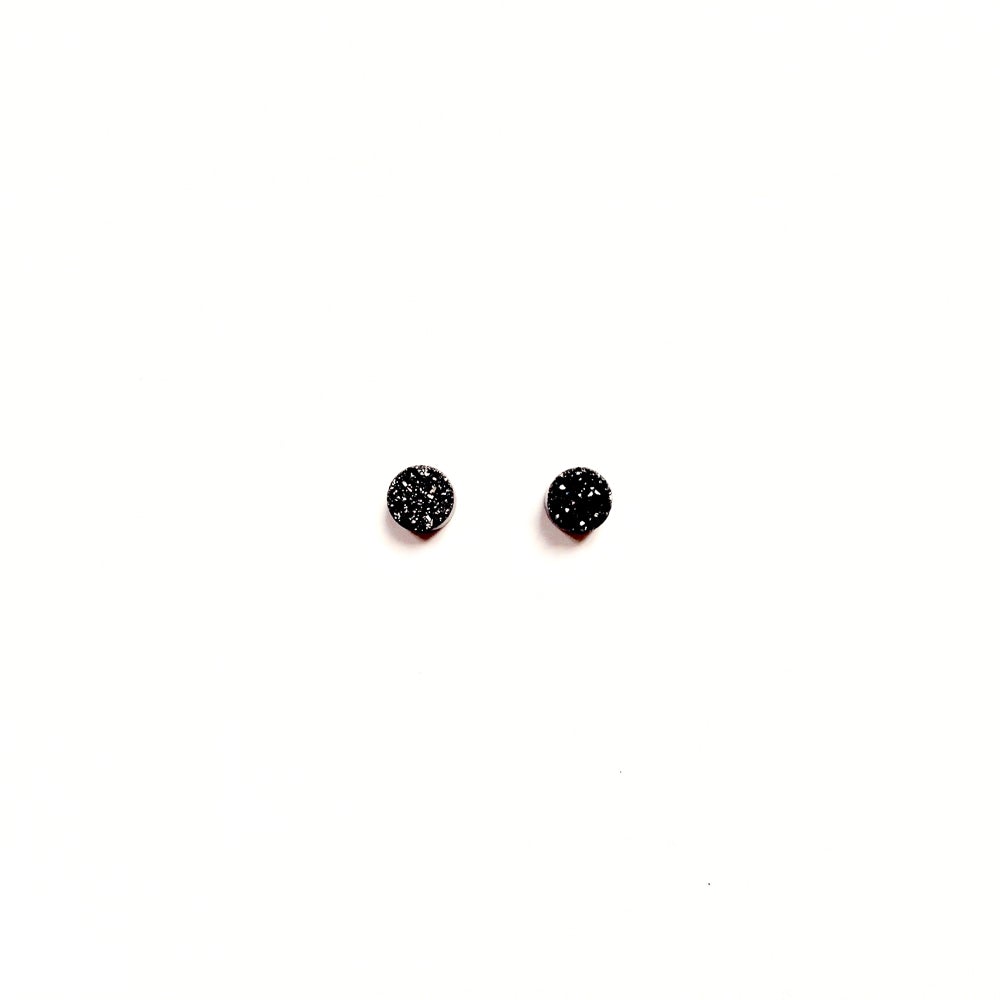 A pair of black stud earrings with glitter particles in them, resembling a crystal.