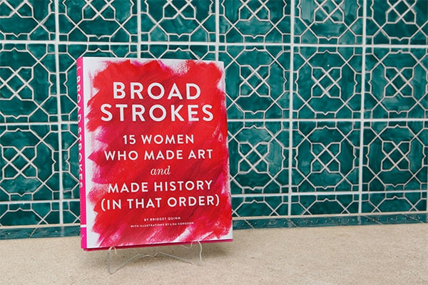 A book is sitting before a tiled wall. The title reads "Broad Strokes: 15 Women Who Made Art and Made History (In That Order)."