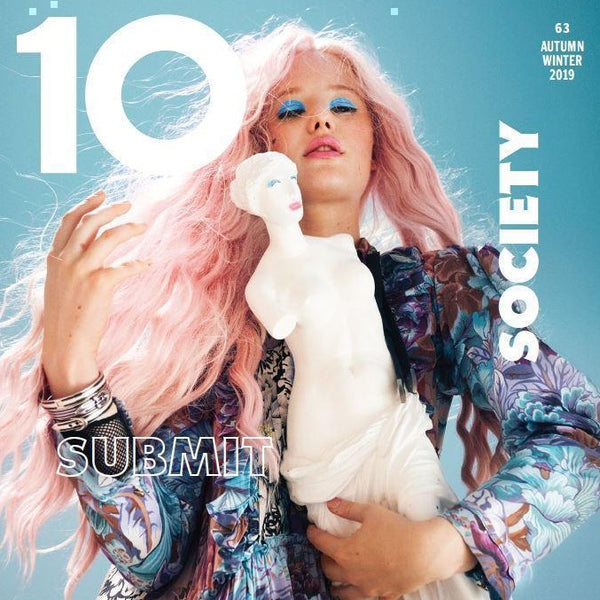 A magazine cover featuring a woman with a light skin tone and pink hair holding an ancient Greek marble sculpture of a woman. In the left upper corner, it says "10" in bold, white letters.