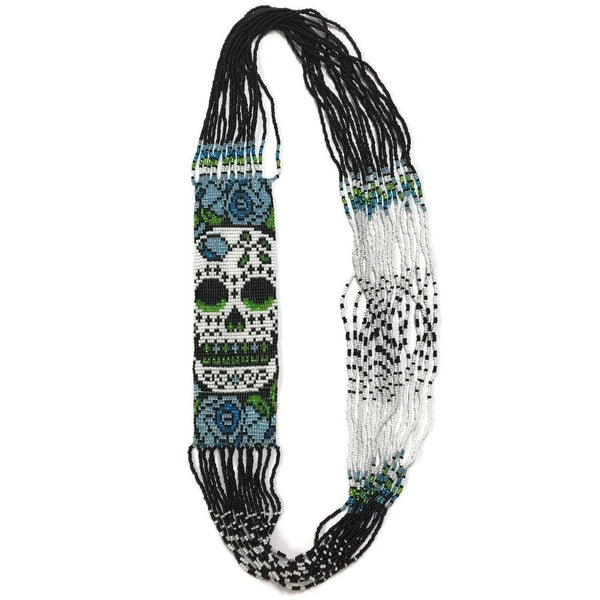 A beaded necklace in black, white, blue and green with a skull pattern. 